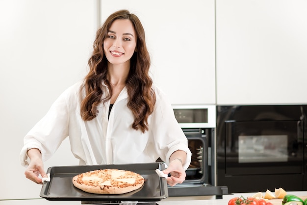 Vrouw die oosterse pizzaschotel kookt bij de keuken