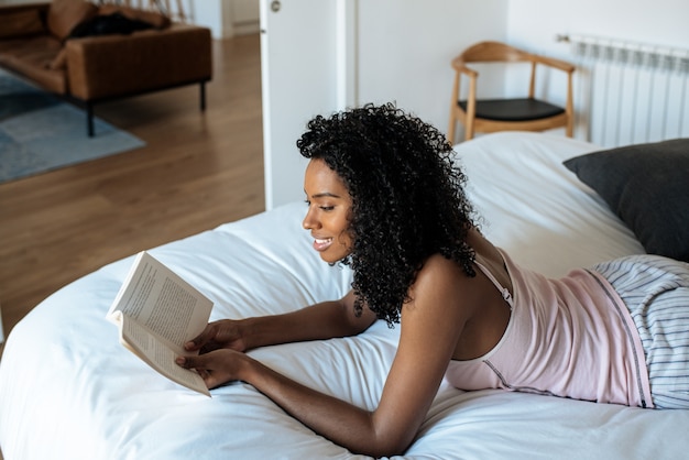 Vrouw die op bed ligt dat een boek leest