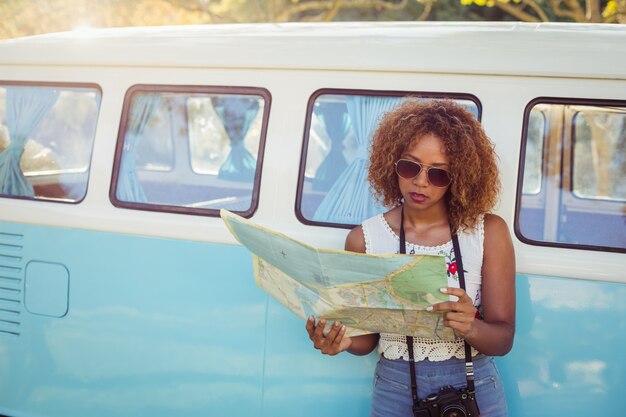 Vrouw die op campervan leunt en kaart bekijkt