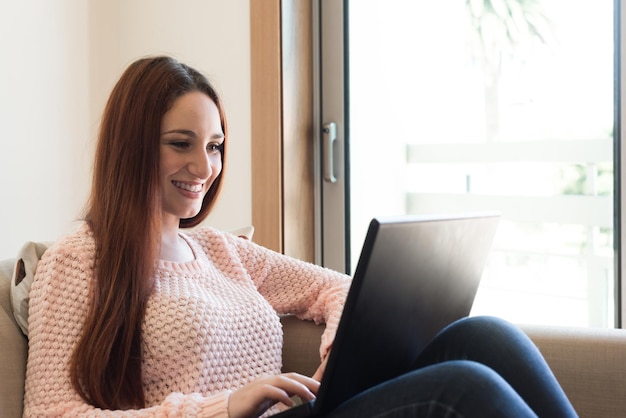 Vrouw die op de bank ligt met een laptop