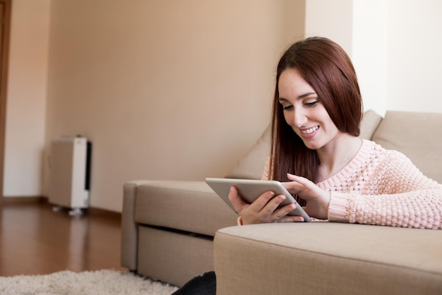 Vrouw die op de bank ligt met een tablet