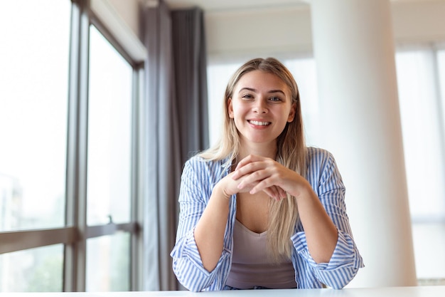 Vrouw die op de computer aan het bureau werkt vanuit huis portret van een mooie vrouw die naar de camera kijkt