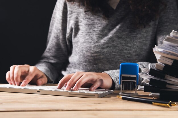 Foto vrouw die op de computer werkt met documenten en zegel op tafel