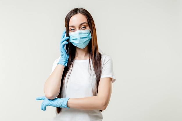 Vrouw die op de telefoon spreekt die masker en handschoenen draagt