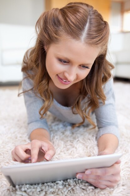 Vrouw die op de vloer ligt die aan haar tablet werkt