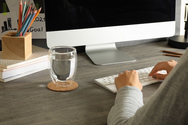 Vrouw die op desktopcomputer op grijze houten tafel werkt