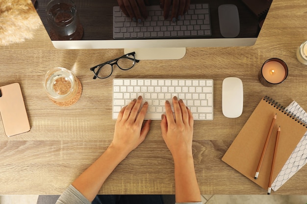 Vrouw die op desktopcomputer op houten tafel werkt