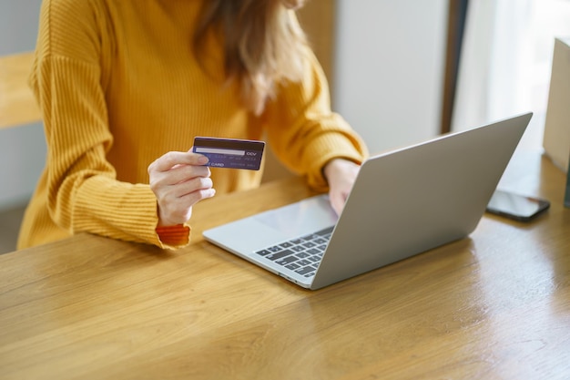 Vrouw die op een laptop winkelt met een creditcard voor internet online e-commerce winkelen geld uitgeven online winkelen mobiele telefoon laptop technologie concept