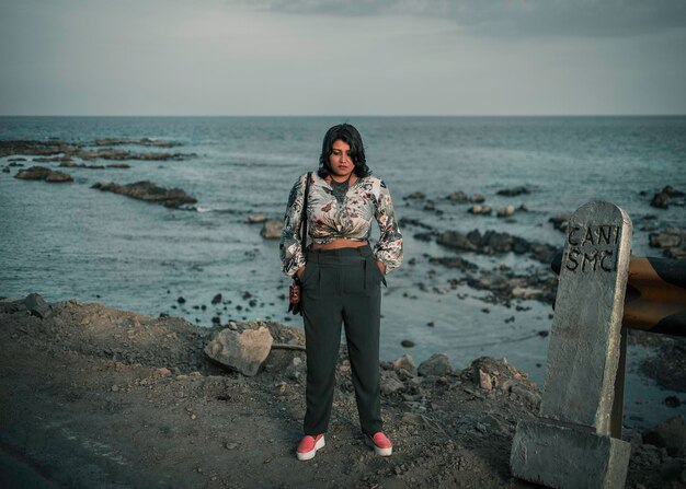 Foto vrouw die op een rots op het strand tegen de lucht staat