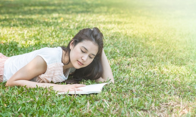 Vrouw die op grasgebied ligt voor het lezen in het park