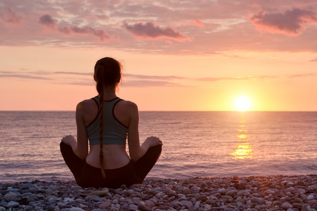 Vrouw die op het strand mediteert. Zonsondergang