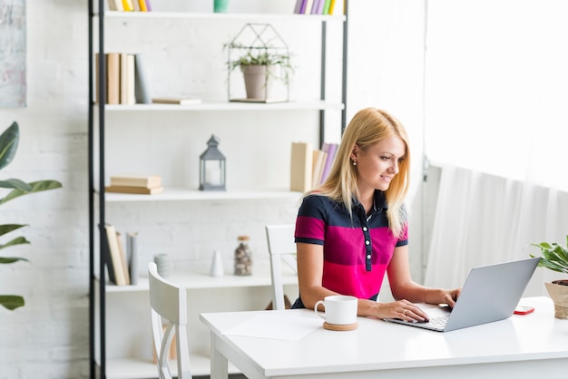 Vrouw die op laptop thuis werkt