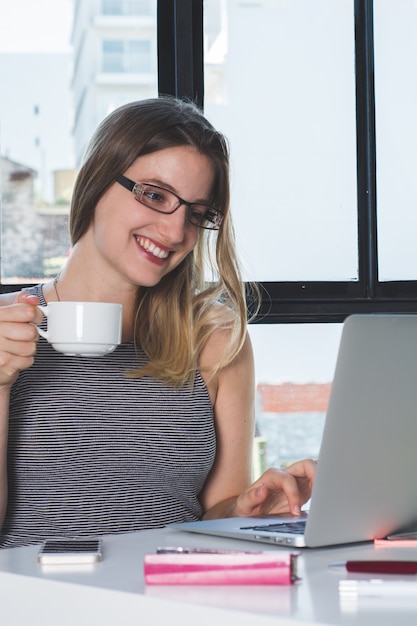 Vrouw die op laptop thuis werkt.