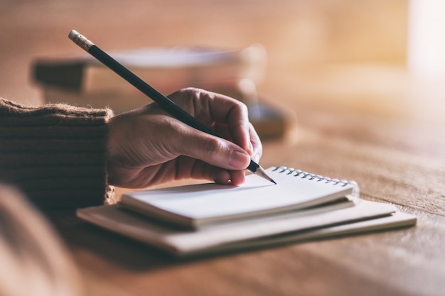 vrouw die op leeg notitieboekje op houten lijst schrijft