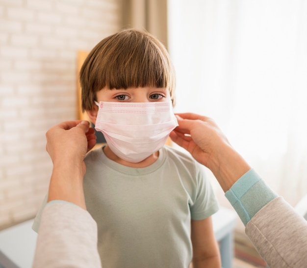 Vrouw die op medisch masker op kind thuis zet