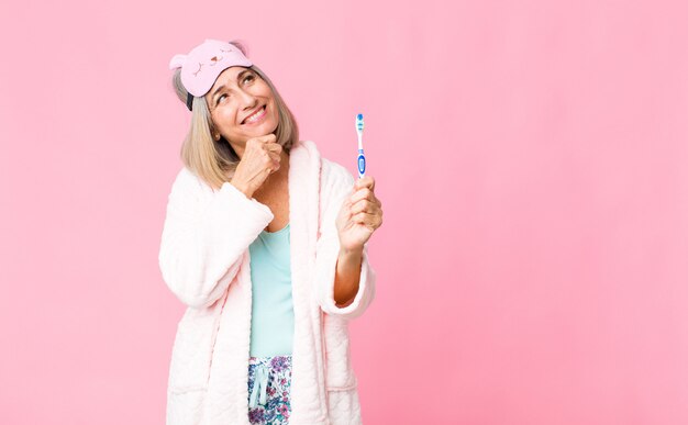 Vrouw die op middelbare leeftijd nachtkostuum met een tandenborstel draagt