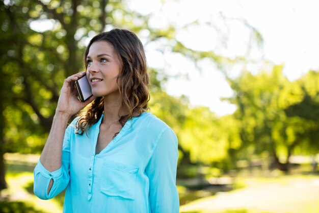 Vrouw die op mobiele telefoon in park spreekt