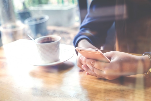 vrouw die op mobiele telefoon tijdens rust in koffiewinkel gebruikt