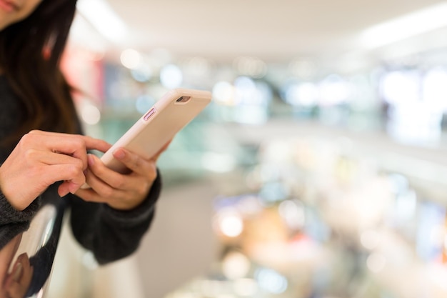 Vrouw die op mobiele telefoon werkt in winkelcentrum