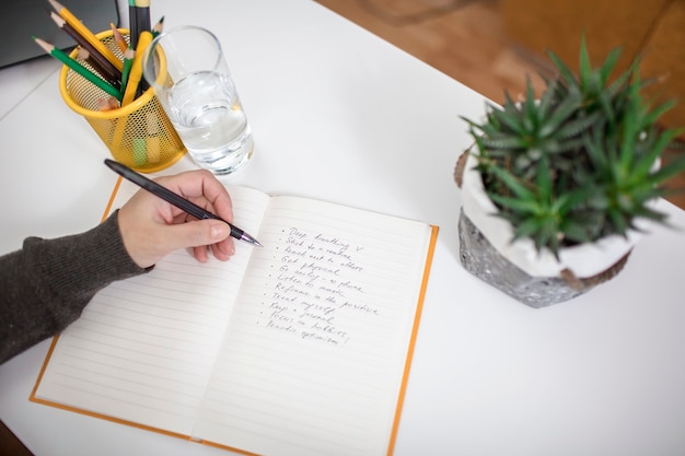 Vrouw die op notitieboekje een lijst met regels voor geestelijke gezondheid schrijft