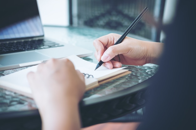 Vrouw die op notitieboekje schrijft