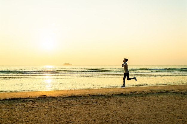 Vrouw die op strand bij zonsopgang loopt