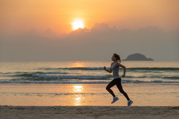 Vrouw die op strand bij zonsopgang loopt