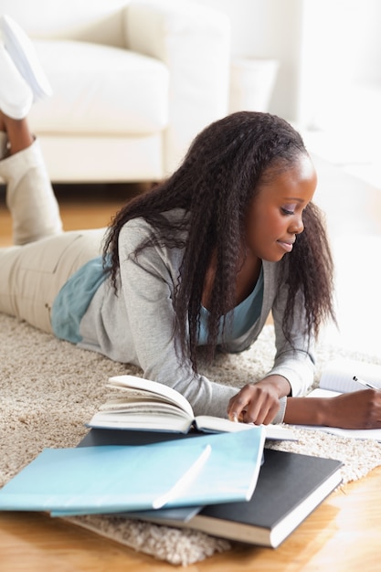 Vrouw die op tapijt ligt dat thuiswerk doet