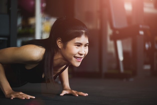 Vrouw die opdrukoefeningen doet bij de gymnastiek. Spier-, bewegings- en gezond leefstijlconcept.