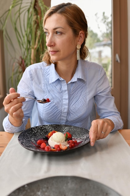 Vrouw die panna cotta eet in een restaurant