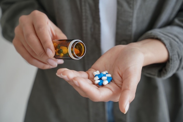Vrouw die pillen vasthoudt, neemt medicijnen pijnstiller vitamines orale anticonceptiva of voedingssupplement