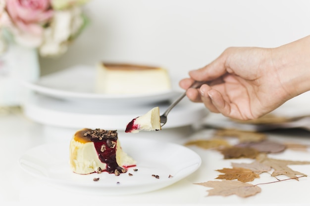 Vrouw die plak van kaastaart met vork eet.