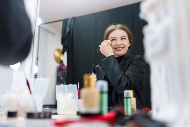 Vrouw die poeder aanbrengt tijdens het opmaken in een backstage