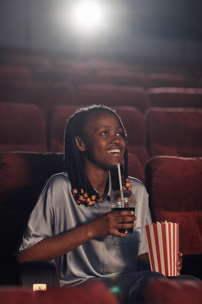 Vrouw die popcorn eet en frisdrank drinkt