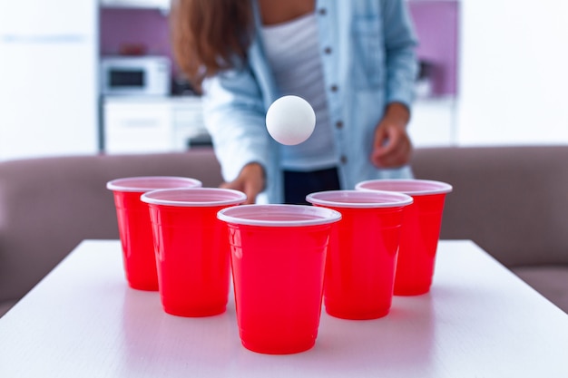 Vrouw die pret hebben en van bier pong spel op lijst genieten thuis