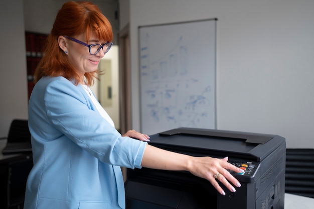 Foto vrouw die printer op kantoor gebruikt