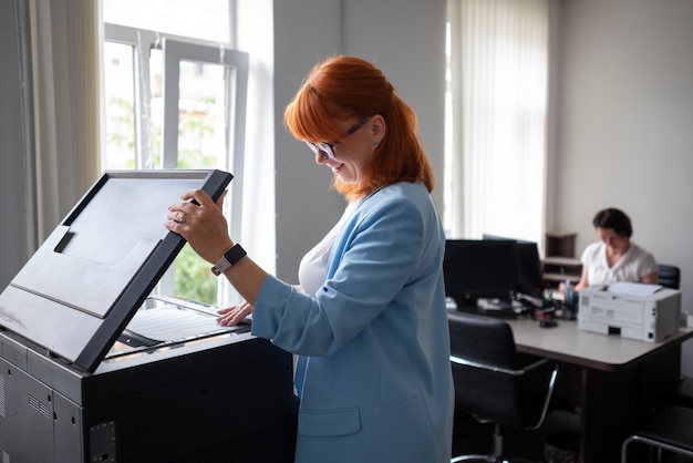 Foto vrouw die printer op kantoor gebruikt