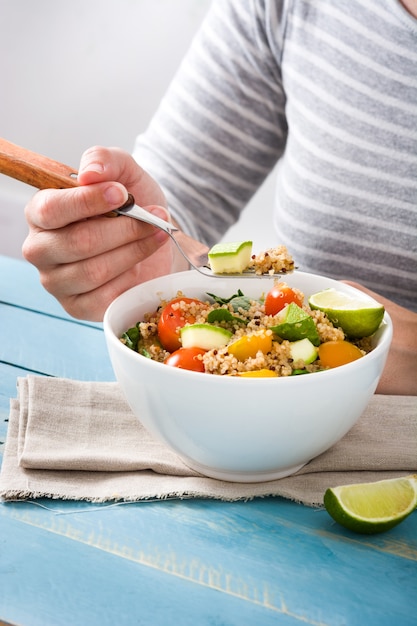 Vrouw die quinoa en groenten eet