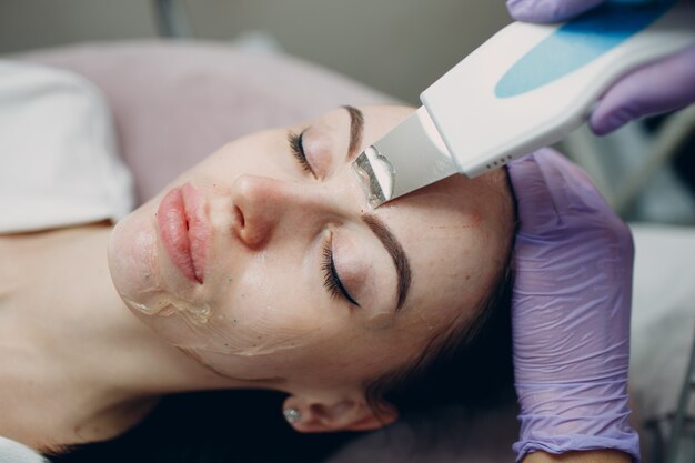 Vrouw die reinigingstherapie met een professionele ultrasone apparatuur in cosmetologie beauty spa ontvangt