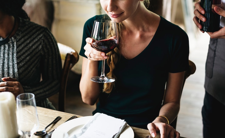 Foto vrouw die rode wijn proeft in een stijlvol restaurant