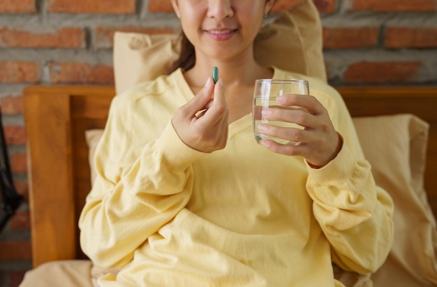 Vrouw die 's ochtends capsulepillen in bed neemt