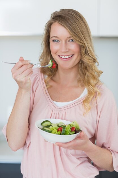 Vrouw die salade in keuken heeft