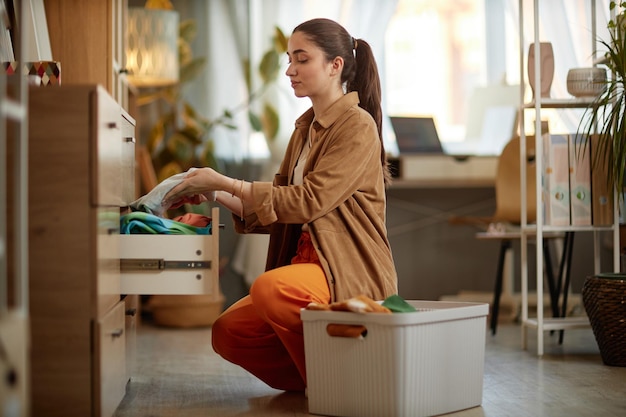 Vrouw die schone kleren in laden opslaat