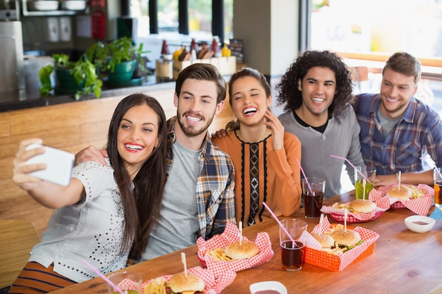Vrouw die selfie met vrolijke vrienden in restaurant