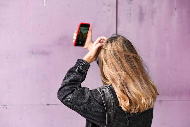 Vrouw die selfie op een grungemuur neemt.