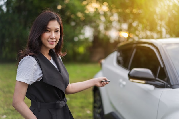 Vrouw die slimme sleutel afgelegen met een auto houdt