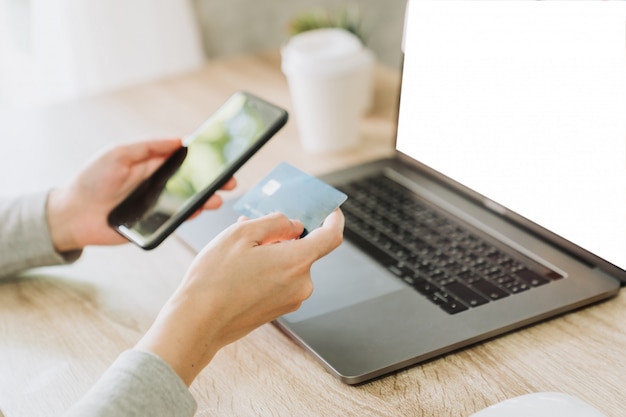 Vrouw die slimme telefoon en creditcard gebruiken om online in koffiewinkel te winkelen