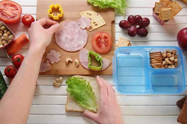 Vrouw die smakelijke sandwich op tafel maakt