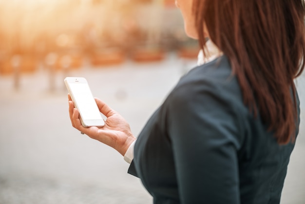 Vrouw die smartphone buiten gebruikt