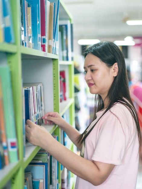 Vrouw die studeert in de bibliotheek vol boeken Conceptie van onderwijs in de moderne interieurbibliotheek